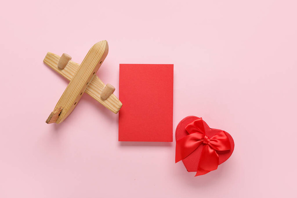 Blank card with gift and wooden airplane on pink background. Valentine's Day celebration - Photo, image