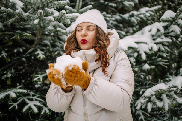 Краса щаслива кавказька жінка насолоджується дме снігом у морозному зимовому парку. Концепція зимових канікул. Високоякісна фотографія - Фото, зображення