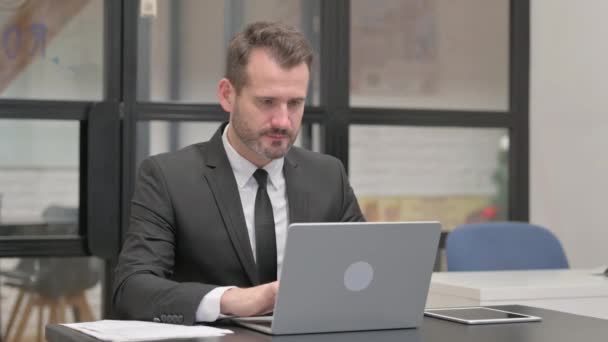 Бизнесмен, страдающий зубной болью во время работы над ноутбуком - Кадры, видео