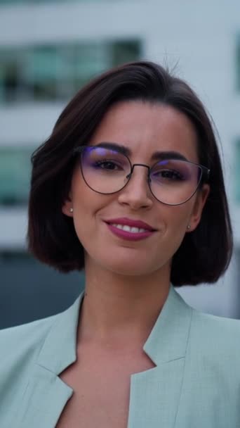 Smiling caucasian young woman in formal outfit looking to camera outside on street while feeling happy. Portrait of business modern manager showing sincere emotions - Materiał filmowy, wideo