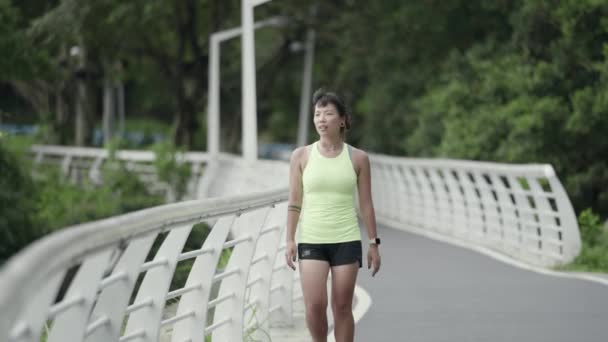 young asian jogger walking resting in park while exercising outdoors - Materiaali, video