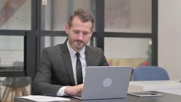 Üzletember a fényképezőgépre mutat, miközben a Laptopon dolgozik - Felvétel, videó