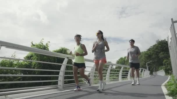 three young asian people man and woman running jogging exercising outdoor in park - Imágenes, Vídeo