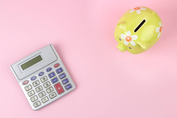 green pig piggy bank and calculator on pink background, money saving concept. top view - Photo, Image