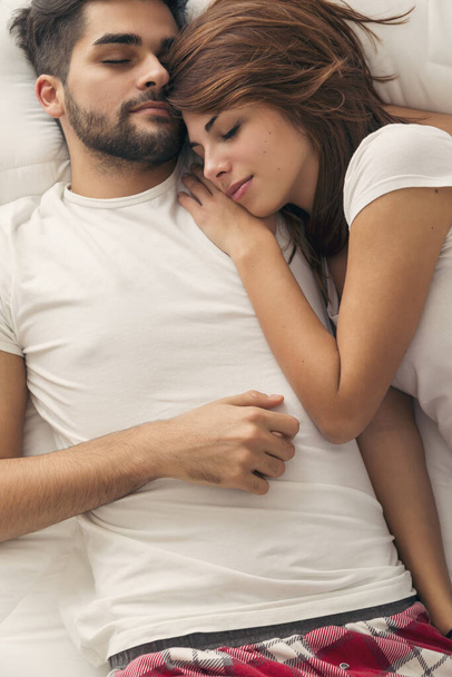 Top view of a couple in love lying hugged in bed, sleeping - Fotó, kép