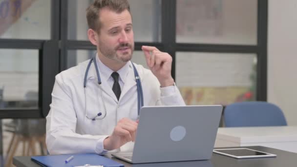 Médico de mediana edad haciendo chat de vídeo a través de ordenador portátil - Metraje, vídeo