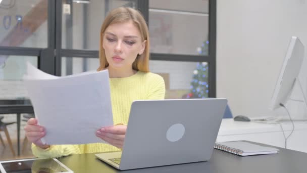 Jonge blonde vrouw werkt aan documenten en laptop - Video