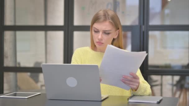 Mujer creativa casual sintiéndose conmocionada mientras trabaja en documentos y computadoras portátiles - Metraje, vídeo