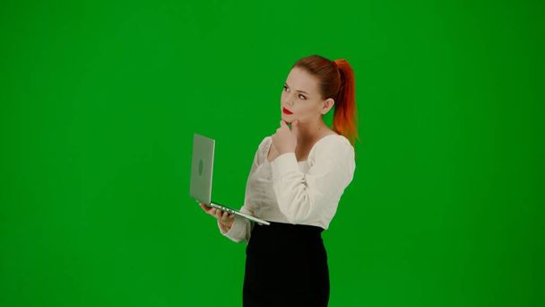 Modern business woman creative advertisement concept. Portrait of attractive office girl on chroma key green screen. Woman in skirt and blouse holding laptop and typing, positive focused expression. - Фото, зображення