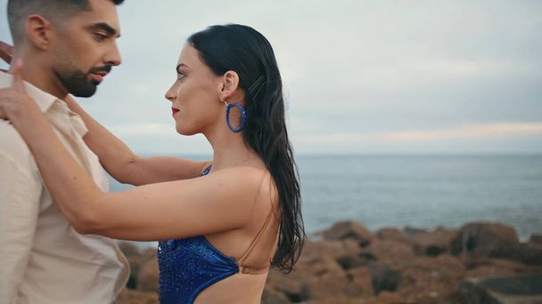 Horké vášnivé latino účinkující tančí společně na zamračeném pobřeží oceánu zblízka. Krásné sexy tanečnice pohybující se s touhou cvičit tango venku. Smyslní partneři vystupující v ponuré přírodě. - Fotografie, Obrázek