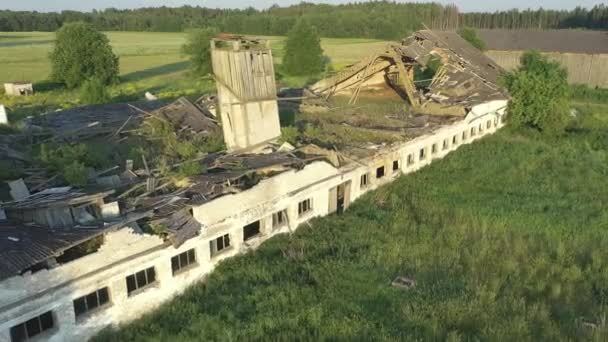 Paide, Estland-5. Juli 2021: Luftaufnahme eines zerstörten Rinderstalls. Das verlassene sowjetische Gebäude zerfällt langsam und wird eins mit der Natur. Drohne bewegt sich langsam rückwärts. - Filmmaterial, Video