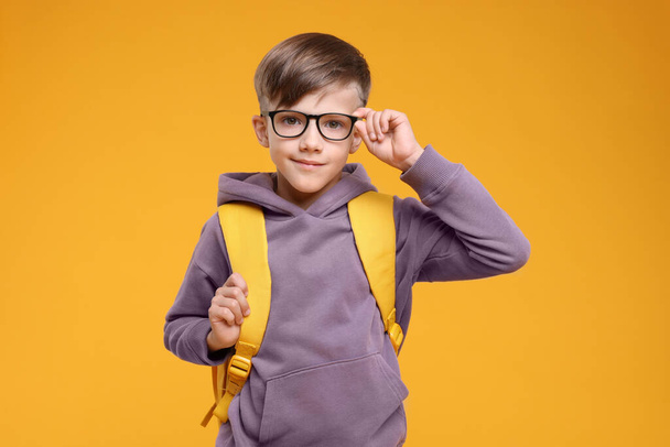Cute schoolboy in glasses on orange background - Фото, зображення