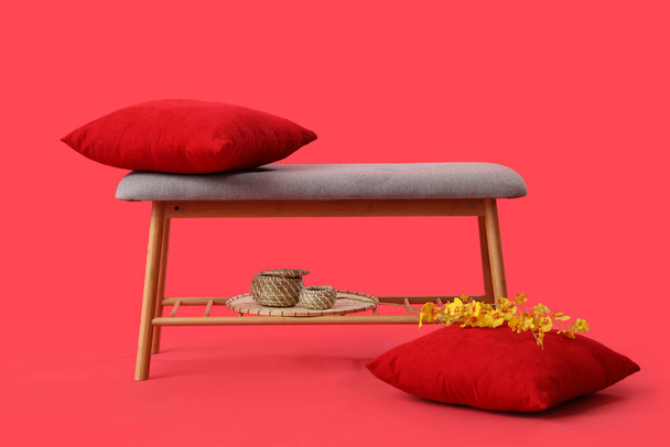 Grey bench with cushions and flowers on red background - Photo, Image