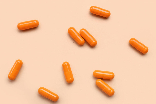 Cápsulas médicas de color naranja sobre fondo beige - Foto, Imagen
