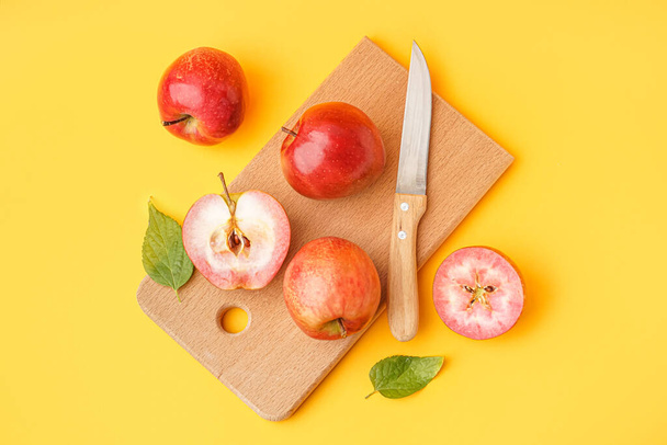 Wooden board with sweet pink apples on yellow background - Foto, Imagen