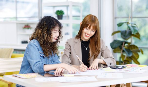 Asijské profesionální úspěšný mladý žena businesswoman kreativní grafický designér rádce mentor v ležérní módní oblek sedí pomáhá výuka nový zaměstnanec pracující na kancelářské pracovní stanici. - Fotografie, Obrázek