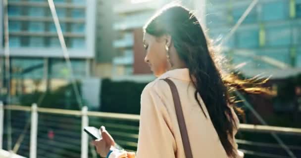 Woman, walking in city with phone and coffee for typing, text message and communication with commute. Business person, travel and sunlight in morning with bag, smartphone and internet conversation. - Footage, Video