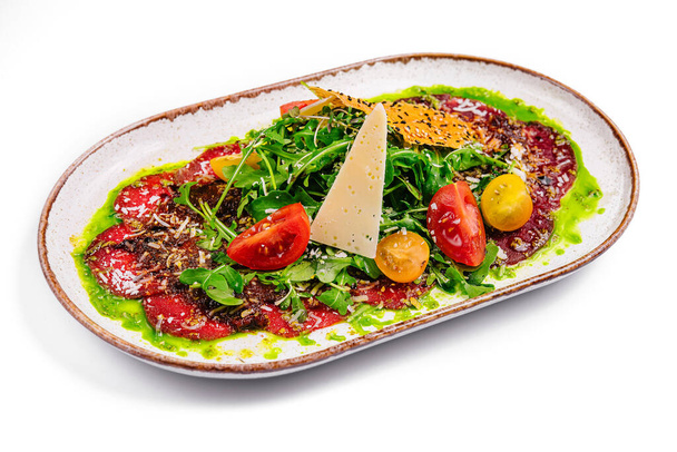 Rindfleisch-Carpaccio mit Parmesan und Rucola auf Teller isoliert - Foto, Bild