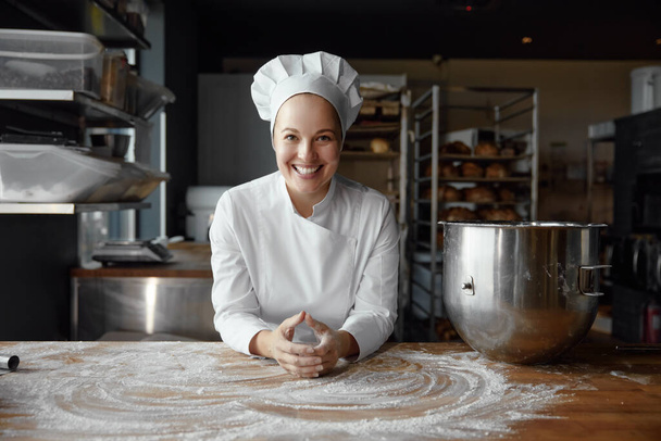 Portrait of happy woman chef baker with smiling face wearing uniform looking at camera. Professional cook at baker kitchen - Photo, Image