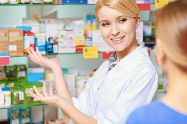 Pharmacist and a customer choosing medicine - Фото, изображение