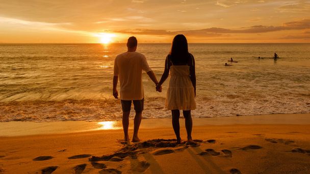 ナイソンビーチプーケットタイで夕日を眺めている男性と女性のカップル, プーケットで有名なサーフスポット, ナイソンビーチで日没. - 写真・画像