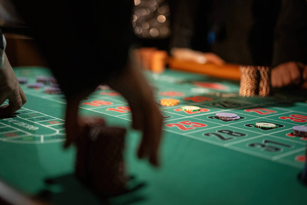 Dramatische Nahaufnahme von Händen, die Wetten auf einen Roulettetisch platzieren und so den Nervenkitzel des Glücksspiels einfangen. - Foto, Bild