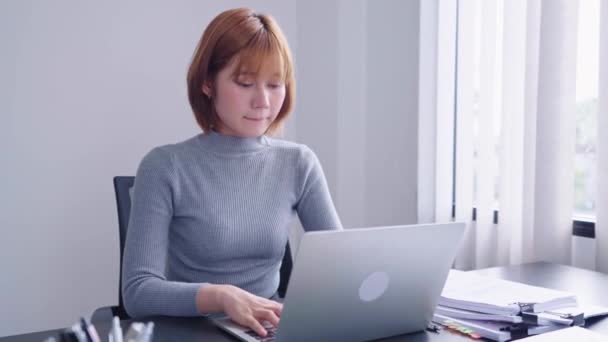 Empresária asiática confiante trabalhando em seu laptop de computador, usando o pensamento analítico para se concentrar em suas tarefas diligentemente. Ela demonstra uma forte ética de trabalho e determinação. - Filmagem, Vídeo