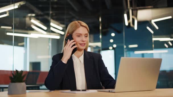Busy woman office worker female manager consulting client by telephone checking information on laptop screen. Professional teleworker broker saleswoman offer goods services remotely using phone laptop - Footage, Video