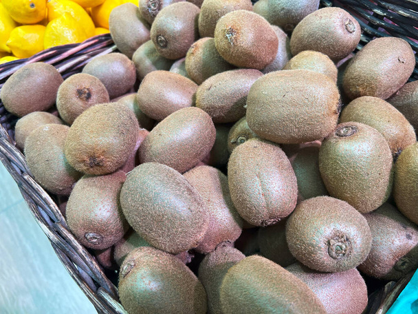 Een stelletje kiwi 's in een mand op een markt.. - Foto, afbeelding