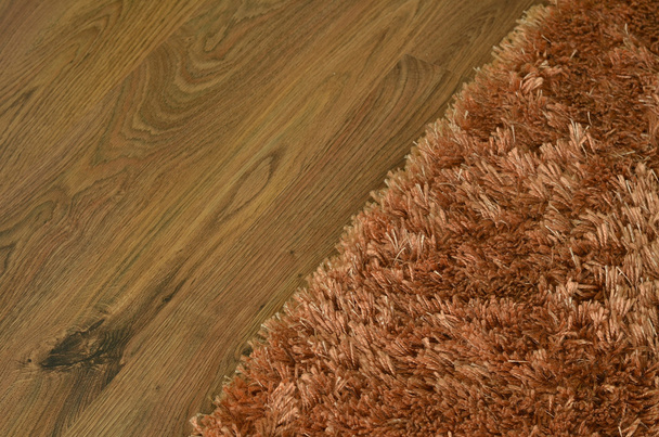 Коричневий кошлатий килим на дерев'яні підлоги - Фото, зображення