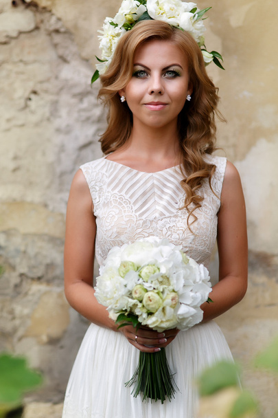 Portrait of the bride with a bouquet and a wreath of white roses - Фото, зображення
