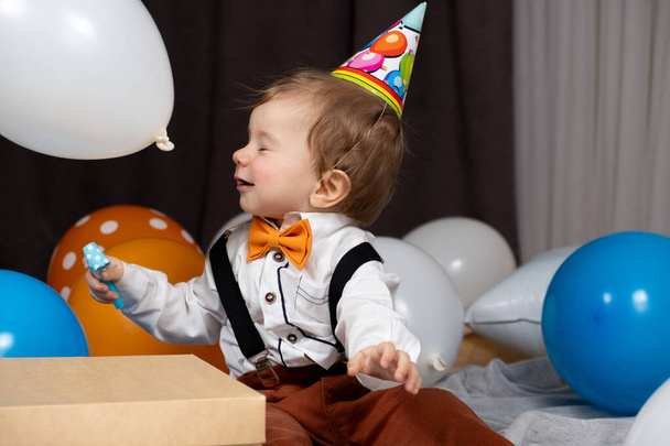 Ребенок празднует свой первый день рождения среди воздушных шаров. - Фото, изображение