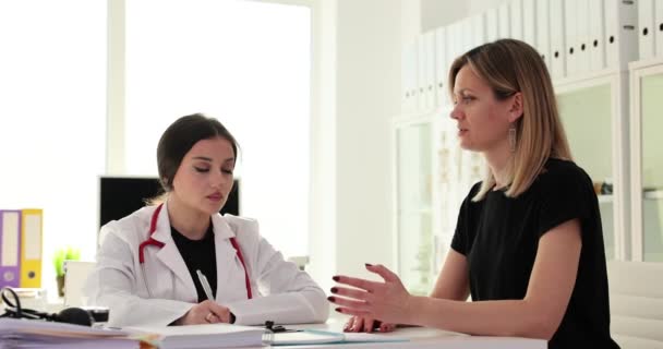 Doctor talking to female patient and asking about complaints in clinic 4k movie slow motion. Medical consultation concept - Video