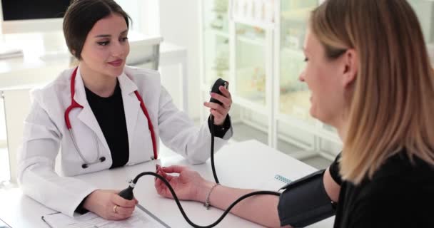 Doctor cardiologist measuring blood pressure of woman patient with tonometer 4k movie slow motion. Treatment of arterial hypertension concept - Video