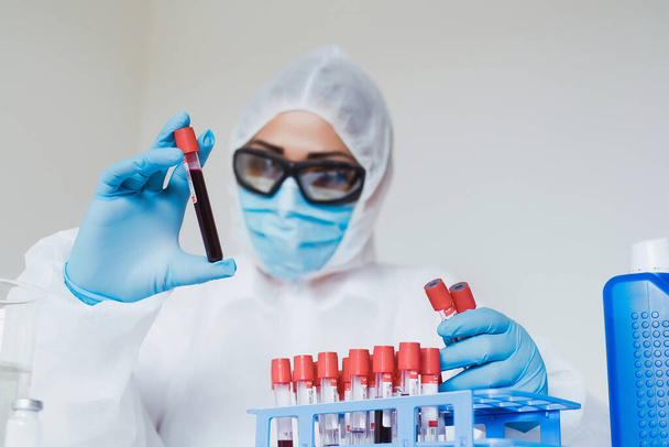Concept d'analyse du coronavirus. Travailleur médical tenant un échantillon de sang en laboratoire avec un test de dépistage de Covid-19 - Photo, image