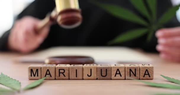 Word marijuana on wooden cubes near judge with gavel closeup 4k movie slow motion. legalization sale of cannabis concept - Video