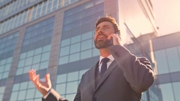 Emotional company owner calling smartphone on street close up. Happy businessman talking cellphone rejoicing success feeling excited outdoors. Joyful manager sharing great news by phone. Camera moving - Footage, Video