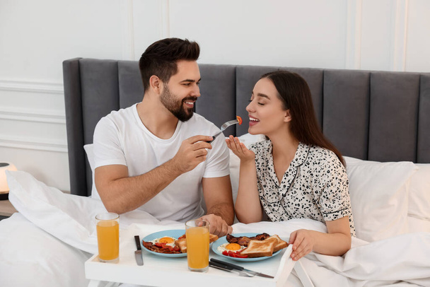 Happy couple having breakfast on bed at home - Φωτογραφία, εικόνα