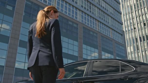 女性の運転手は,都市の通りを立っている高価な黒い車に座ります. 成功したエレガントなビジネスマンは,運転する古典的な自動車を開きます. 自信のある女性は高級車に屋外を歩いています. - 映像、動画