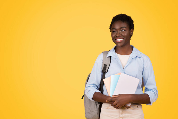 A focused black woman student, immersed in studies with pile of books, expression serious and studious, striking yellow background, epitomizing essence of academic dedication and learning - Fotoğraf, Görsel