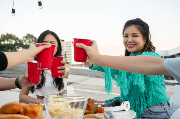 Skupina mladých asijských přátel paří na střešním baru a připíjí si na pití. Šťastní mladí lidé s pivem. oslavy a noční život koncept. detailní záběr - Fotografie, Obrázek