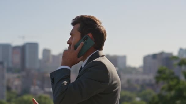 Bearded executive speaking cellphone on street close up. Confident businessman calling partners standing sunny city panorama in elegant suit. Wealthy man manager discussing work. Camera moving around - Footage, Video