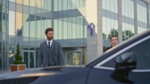 Business people getting in car hurrying at meeting. Two corporate partners walking to expensive black automobile sit down inside. Elegant bearded man opening door to driver seat. Teamwork concept. - Footage, Video