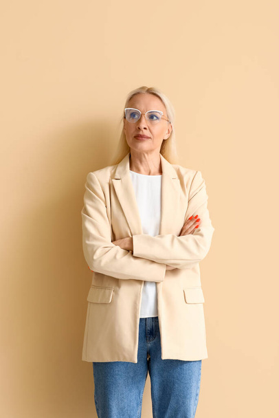 Mujer rubia madura en gafas graduadas sobre fondo beige - Foto, Imagen