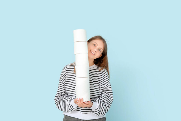 Woman holding stack of toilet paper rolls on color background - Fotografie, Obrázek
