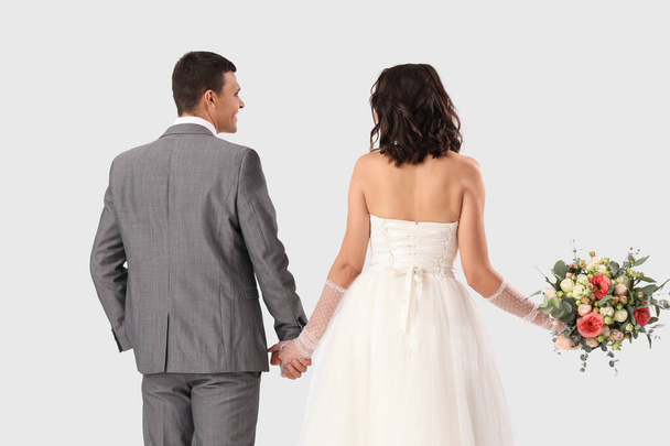 Young wedding couple with bouquet of flowers on white background, back view - Φωτογραφία, εικόνα