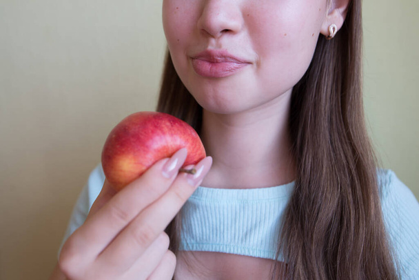 young beautiful girl eating an apple, close-up, crop photo. - Fotó, kép
