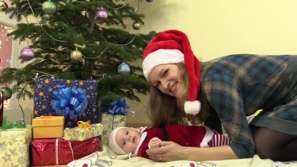 Madre con la hija del bebé en la ropa de Navidad mira a la cámara
 - Metraje, vídeo