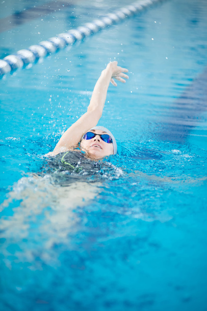 Young girl in goggles swimming back crawl stroke style - Zdjęcie, obraz