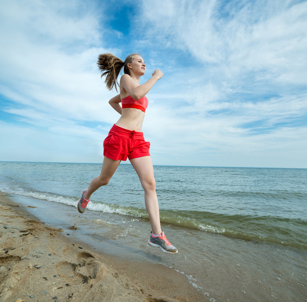 Young lady running at the sunny summer sand beach. Workout.  Jog - Fotoğraf, Görsel